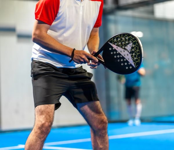 Cropped photo of the lower part of an unrecognizable mature sportive man playing paddle tennis in an indoor court